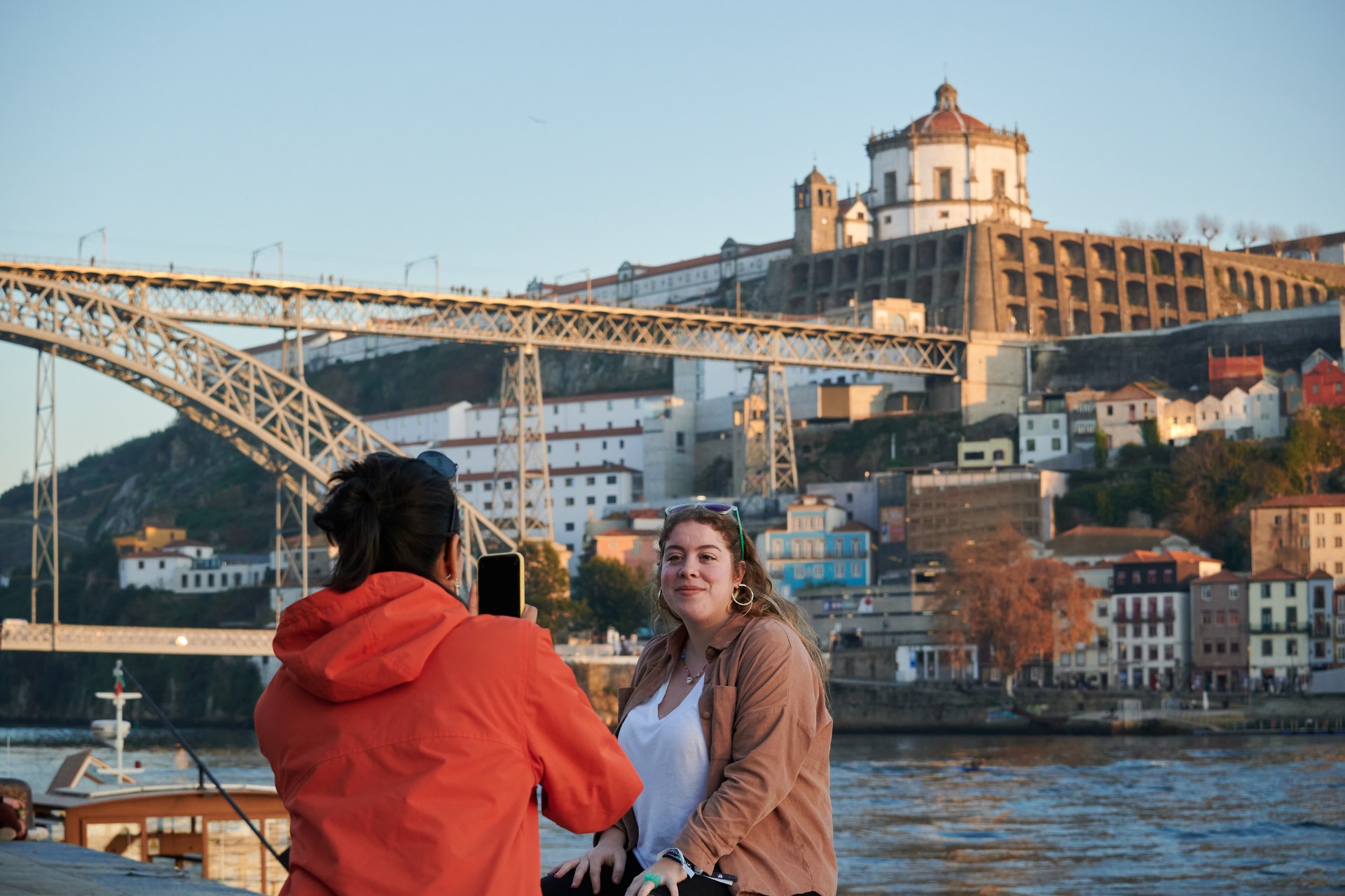 شابة تلتقط صورة لصديقتها وخلفها أحد جسور بورتو